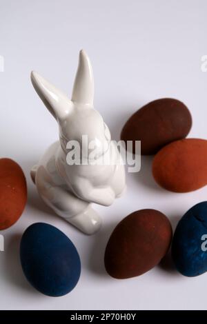 Foto eines anders bemalten Eies und eines weißen Kaninchens auf weißem Hintergrund Stockfoto