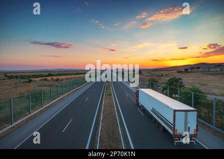 Fahrt auf offener Straße bei wunderschönem Sonnenuntergang. Luftaufnahme Stockfoto