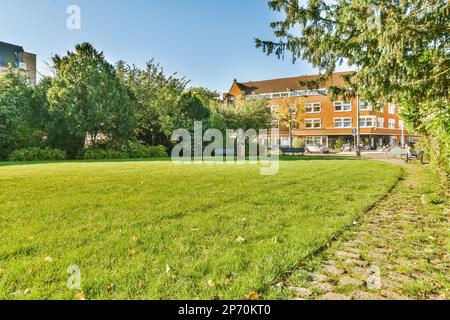 Amsterdam, Niederlande - 10. April 2021: Ein Außenblick auf den Hinterhof mit Bäumen und Gras im Rasen ist von hohen roten Ziegelgebäuden umgeben Stockfoto