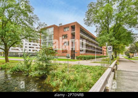 Ein Backsteingebäude mit Bäumen vorne und Wasser fließt von seiner Seite zu den anderen Gebäuden auf beiden Seiten Stockfoto