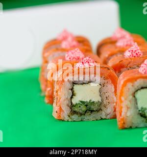Sushi mit Lachs und Frischkäse auf grünem Hintergrund. Nahaufnahme Stockfoto