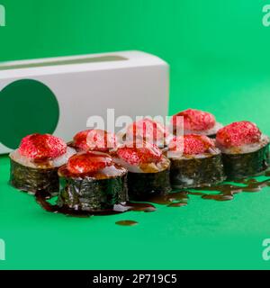 Sushi mit Meeresfrüchten in Nori auf grünem Hintergrund. Nahaufnahme Stockfoto