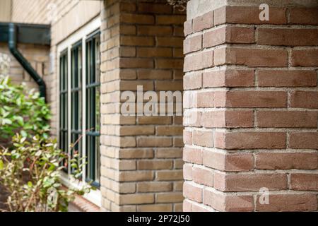 Amsterdam, Niederlande - 10. April 2021: Ein Ziegelgebäude mit einer Uhr auf der Seite und einigen Büschen im Vordergrund - Augenbereich dahinter Stockfoto