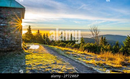 Ein frostiger, sonniger Morgen mit Sonnenstrahlen, die durch einen Steinunterschlupf im Jeleni studanka im Hruby-Jesenik-Gebirge in der Tschechischen Republik scheinen Stockfoto