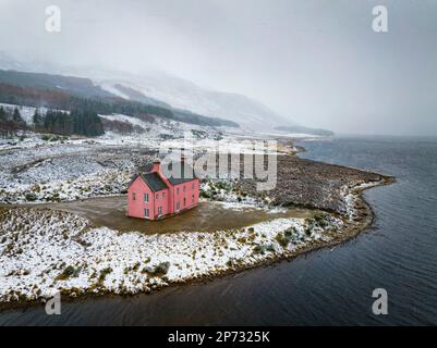 Die Culzie Lodge, auch bekannt als das Pink House in Snow am Ufer des Loch Glass in Easter Ross, Schottland, aus der Vogelperspektive Stockfoto
