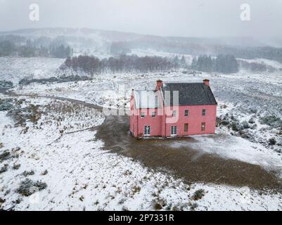 Die Culzie Lodge, auch bekannt als das Pink House in Snow am Ufer des Loch Glass in Easter Ross, Schottland, aus der Vogelperspektive Stockfoto