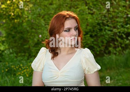 Porträt eines jungen rothaarigen Mädchens in grüner Natur, das zur Seite blickt Stockfoto