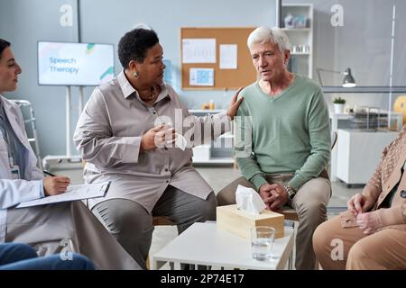Porträt eines erfahrenen weißhaarigen Mannes, der Gefühle in der psychischen Unterstützungsgruppe im Seniorenheim teilt Stockfoto