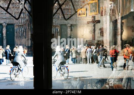 Straßburg, Frankreich - 20. März 2015: Abstrakte Kathedrale Notre Dame de Strasbourg Haupteingangsfassade mit Silhouetten von Menschen, Fußgänger, Einheimische und Touristen, die sich im nahegelegenen Fenster mit einem Souvenirladen widerspiegeln Stockfoto