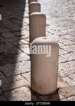 Betonpfosten auf einem Gehweg aus Fliesen an sonnigen Tagen Stockfoto