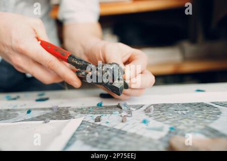 Handwerker Schneiden von Smaltglas mit Zangen Cutter für die Herstellung von Smaltglas Mosaik Stockfoto