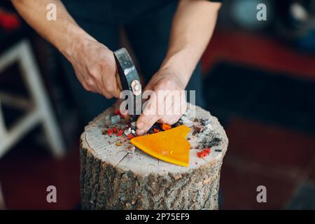 Handwerker schneidet zerbrechendes Smaltglas mit Hammer für Mosaikkunstwerke in der Werkstatt. Stockfoto