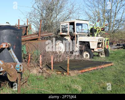 Ein Traktor in der Ecke eines Feldes, jetzt stillgelegt und eingerostet Stockfoto