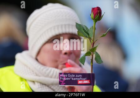 Hennigsdorf, Deutschland. 08. März 2023. Der Teilnehmer einer Demonstration zum Internationalen Frauentag hält eine Rose mit der Botschaft "Happy Women's* Right Day!". Kredit: Soeren Stache/dpa/Alamy Live News Stockfoto