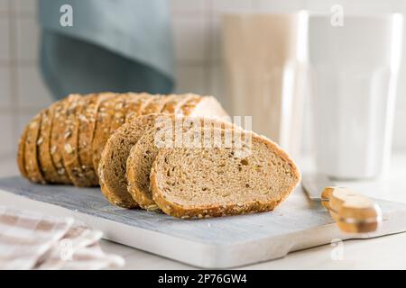 Scheiben Vollkornbrot. Leckeres Vollkorngebäck mit Samen auf dem Schneidebrett. Stockfoto