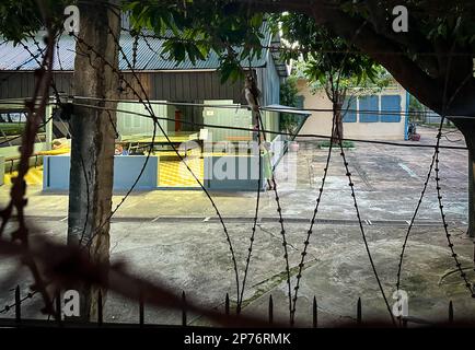 Ein Blick hinter dem Rasierdraht eines Jungen auf dem Gelände des Museums im ehemaligen Foltertod-Camp der Roten Khmer Tuol Sleng in Phnom Penh, Kambodscha. Stockfoto