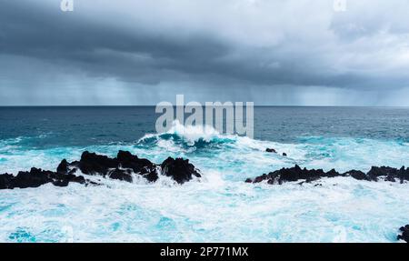 Wellen schlagen auf Felsen und bilden große Wassersäulen Stockfoto