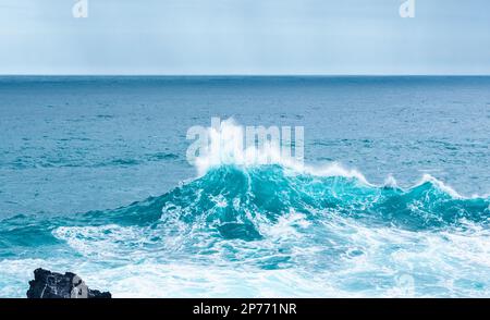 Wellen schlagen auf Felsen und bilden große Wassersäulen Stockfoto