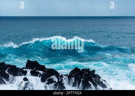 Wellen schlagen auf Felsen und bilden große Wassersäulen Stockfoto