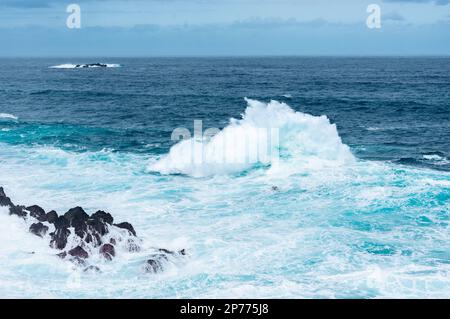 Wellen schlagen auf Felsen und bilden große Wassersäulen Stockfoto