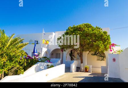 Traditionelle kykladische weiße Villa mit blühenden rosa Bougainvillea-Sträuchern auf dem Gipfel im Dorf Kamari am Strand, Insel Santorini Ostküste, Griechenland Stockfoto