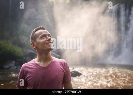 Porträt des Reisenden vor dem Hochwasserfall. Glücklicher Mann in tropischer Natur in Kambodscha. Stockfoto