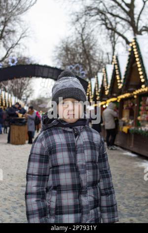 Der einsame Junge stand auf einer Weihnachtsmesse und schaute zu Stockfoto