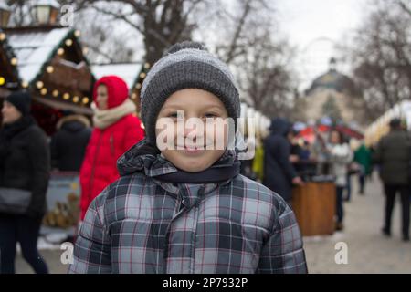 Ein Lächeln auf dem Gesicht eines Jungen im Winter auf einer Weihnachtsmesse Stockfoto