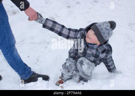 Der Junge hilft, den Jungen aus dem Schnee zu holen Stockfoto