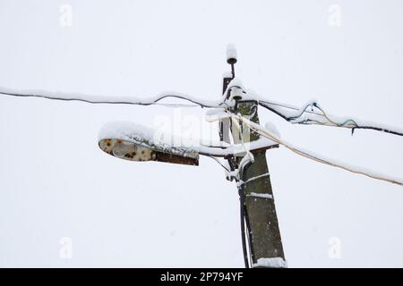 Viel Schnee in der Reihe von elektrischen Kabeln und Lampen Stockfoto