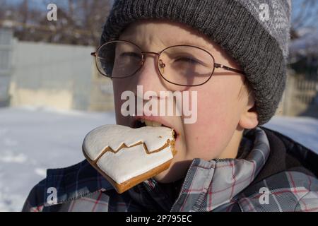 Im Winter isst der Junge auf der Straße Kekse Stockfoto