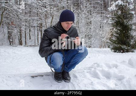 Ein Videofilmer nimmt im Winter im Schnee im Park Naturaufnahmen auf Stockfoto