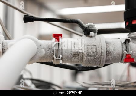 Flüssigstickstoff-gefrorener Wasserhahn und Metallrohre in einer Forschungseinrichtung, isolierte Nahaufnahme. Stockfoto