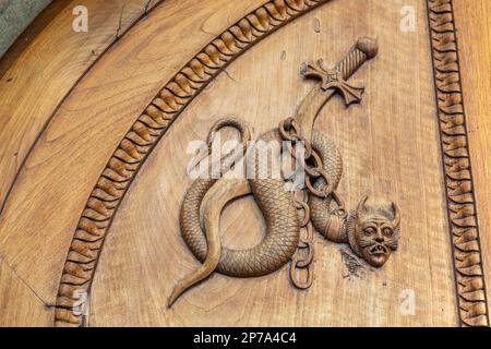 Teufelsschlangen-Symbol. Ein magisches Geschöpf der Fantasie an einer alten Tür, Abtei aus dem 12. Jahrhundert, Italien Stockfoto