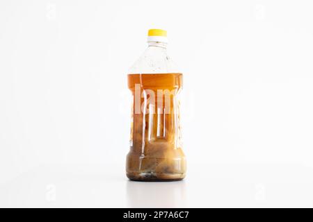 Gebrauchtes Sonnenblumenöl in einer Plastikflasche. Verbrannte gebratene Fußreste und dicke Fettsedimente auf dem Boden. Bereit zur Wiederverwertung als Biokraftstoff Stockfoto