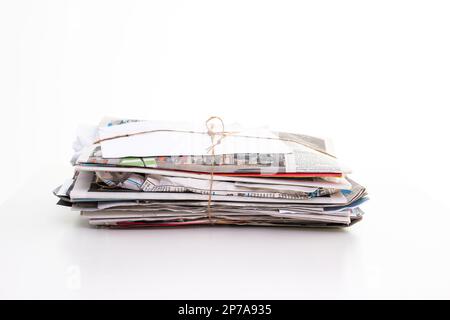 Gestapelter, gepresster und verpackter Hauspapiermüll, der für das Recycling abgeholt werden kann. Nahaufnahme Studio, isoliert auf Weiß, keine Leute. Stockfoto