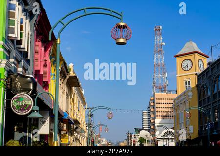 Farbenfrohe Geschäfte im chinesisch-portugiesischen Stil in der Phang-Nga Rd In der Altstadt von Phuket Town, Thailand, mit dem berühmten Phromthep Clocktower in b/g Stockfoto