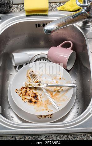 Dreckiges Geschirr im Waschbecken. Porzellangeschirr und Utensilien mit Essenssoße, keine Menschen, Top-Aussicht. Stockfoto