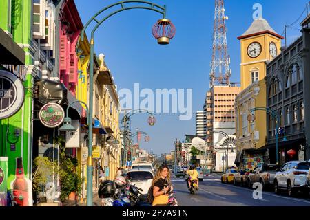 Farbenfrohe Geschäfte im chinesisch-portugiesischen Stil in der Phang-Nga Rd In der Altstadt von Phuket Town, Thailand, mit dem berühmten Phromthep Clocktower in b/g Stockfoto