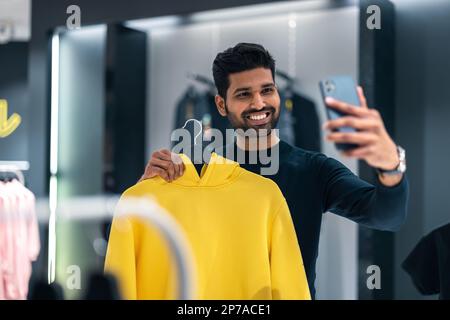 Junger Mann, der im Bekleidungsgeschäft einkauft Stockfoto