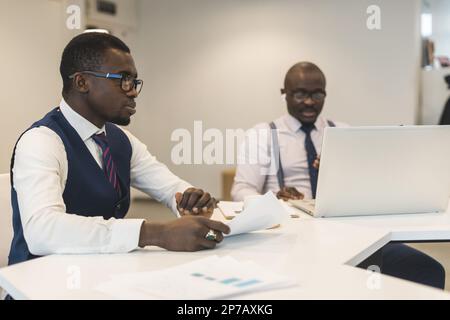 Zwei afroamerikanische Geschäftspartner arbeiten gemeinsam an einem Laptop an einem gemeinsamen Projekt. Coworking, soziale Kontakte und Remote Networking Stockfoto