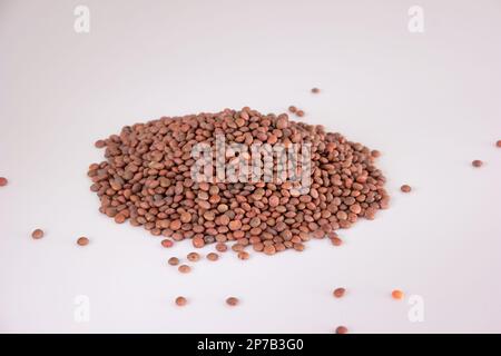 Rohe, ungekochte Linsen stapeln sich auf weißem Hintergrund, Draufsicht, keine Menschen. Stockfoto