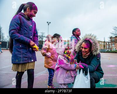 Den Haag. Niederlande, 07./03./2023. Eine Frau zeigt ihrem kleinen Mädchen während des Holi Festivals in Den Haag, wie man mit einer gefälschten Pistole bunten Puder wirft. Millionen Menschen auf der ganzen Welt feiern das jährliche Holi Hangámá Festival. In Den Haag, wo die größte indische Bevölkerung Europas zu finden ist, fand eine große Feier im multikulturellen transvaalen Viertel statt, wo die Teilnehmer bunt bunten Puder auf sich selbst und auf einander werfen. Diese Feier, auch bekannt als Fest der Farben, ist die Feier der Ankunft des Frühlings, eines Neubeginns und des Triumphes von Stockfoto