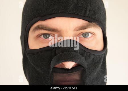 Weiß, männliches Gesicht, trägt eine schwarze Skimaske aus Stoff. Nahaufnahme, nicht erkennbar. Stockfoto