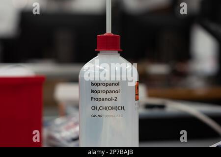 Isopropanol-Plastikflasche und Dispenser. Nahaufnahme in einem Labor. Geringe Schärfentiefe, keine Menschen. Stockfoto