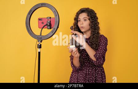 Schockiert Kind Blogger mit langen lockigen Haaren machen Video für Blog halten Puderbürste Stockfoto