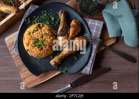 Gebackene Hähnchenschenkel mit Gemüse-Reis oder serbischem Djuvec-Reis auf einem Teller. Stockfoto