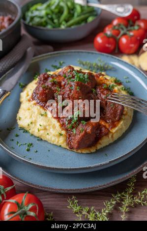 Fleischgericht am sonntag oder im Urlaub mit einem köstlichen italienischen Ragout, cremigen Polenta und grünen Bohnen auf einem Teller Stockfoto