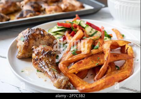 Gegrilltes Hähnchen mit Süßkartoffeln und mediterranem Salat auf einem Teller Stockfoto