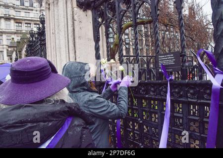 London, Großbritannien. 8. März 2023 Ein Demonstrant hängt Blumen an den Zaun vor dem Parlament. Die Rentner trafen sich am Internationalen Frauentag auf dem Parlamentsplatz, um gegen die Ungleichheit der Renten zu protestieren, und forderten Gerechtigkeit für die in den 1950er Jahren geborenen Frauen, die laut Demonstranten ihrer Rente "beraubt" wurden. Die Demonstration wurde von der WASPI (Women Against State Pension Inequality) organisiert. Kredit: Vuk Valcic/Alamy Live News Stockfoto